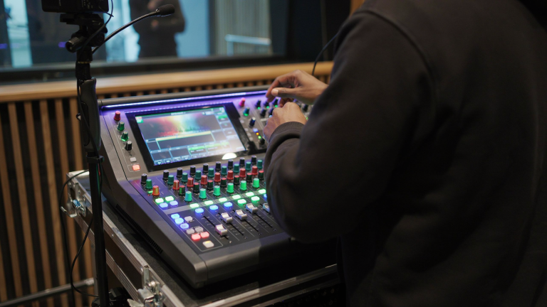 Audio engineer operating a digital mixing console in a production studio