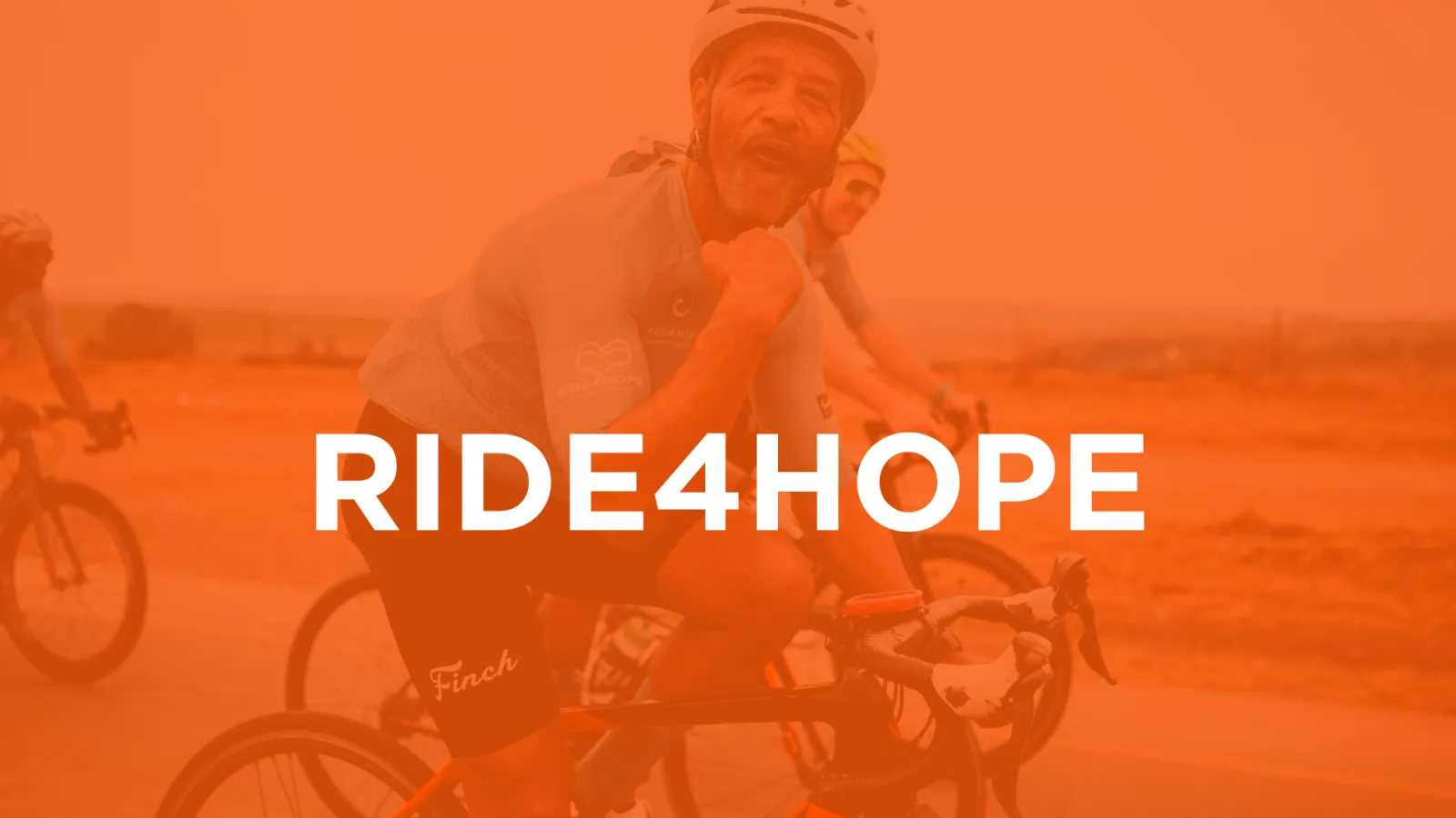 Legacy Ride4Hope cyclist on the road beneath orange Ride4Hope title artwork
